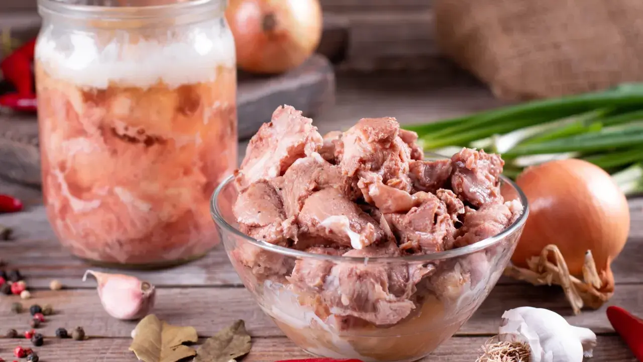 Słoik z mięsem i miska pełna smakołyków, cebula, czosnek, papryczki chili i liście laurowe. To składniki na obiady jak u babci przepisy.