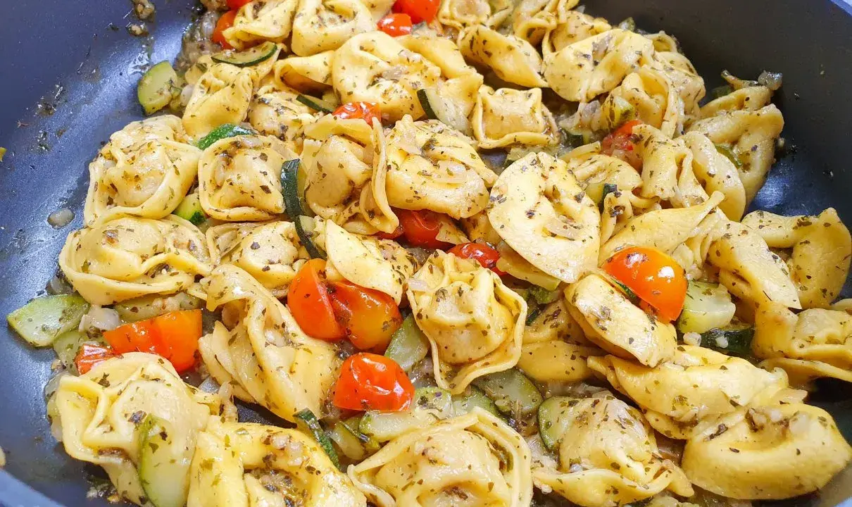 Jak ugotować tortellini z cukinią i pomidorkami koktajlowymi. Danie wygląda apetycznie i jest gotowe do podania.