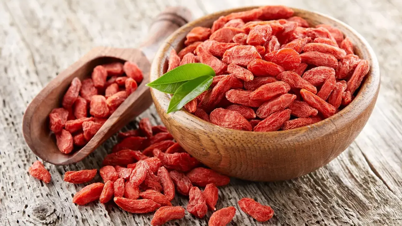 Suszone jagody goji w drewnianej misce i łopatce. Uważaj na jagody goji skutki uboczne, choć są zdrowe, mogą wchodzić w interakcje z lekami.