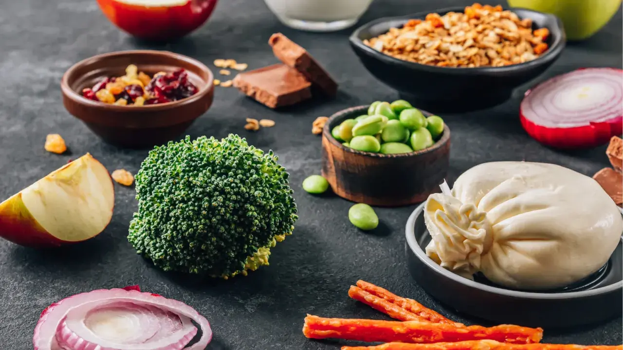 Składniki na dietę dr Budwig: brokuły, fasolka edamame, twaróg, jabłka, cebula, granola, suszone owoce, czekolada.