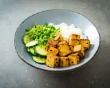 Misternie pokrojone kostki tofu, które nie zawierają glutenu, podane z ryżem, ogórkiem i zielonym groszkiem.