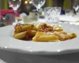 Pyszny makaron paccheri w sosie pomidorowym, podany na białym talerzu.