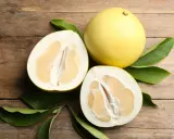 Całe i przekrojone pomelo na drewnianym tle. Czy pomelo jest zdrowe? Tak, to pyszny i odżywczy owoc.