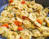 Jak ugotować tortellini z cukinią i pomidorkami koktajlowymi. Danie wygląda apetycznie i jest gotowe do podania.