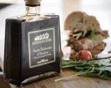 Butelka octu balsamicznego z Modeny obok kanapki i rukoli. Ocet winny i balsamiczny to dwa różne smaki.