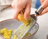 Ręce trą imbir na tarce, przygotowując naturalny sposób na zgagę w nocy.