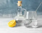 Szklanka z wodą i octem spirytusowym, cytryna obok. Czy ocet spirytusowy jest zdrowy? Warto to sprawdzić.