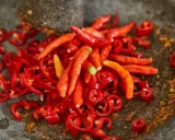 Kawałki i całe papryczki chili w moździerzu. Przygotowanie najostrzejszego jedzenia na świecie.