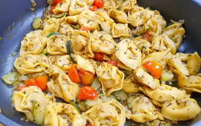 Jak ugotować tortellini z cukinią i pomidorkami koktajlowymi. Danie wygląda apetycznie i jest gotowe do podania.