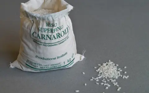 Worek z ryżem Carnaroli, idealnym do risotto. Kilka ziaren rozsypanych obok.