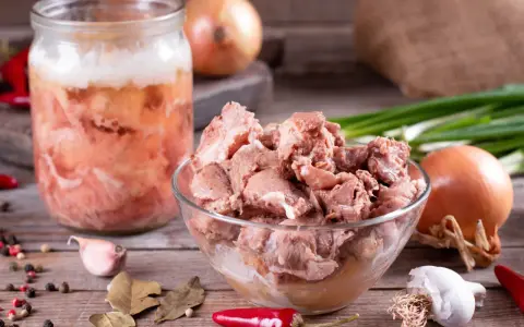 Słoik z mięsem i miska pełna smakołyków, cebula, czosnek, papryczki chili i liście laurowe. To składniki na obiady jak u babci przepisy.