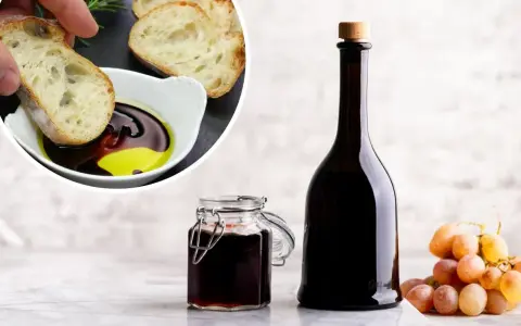 Chleb maczany w oliwie i occie balsamicznym, butelka i słoiczek z octem, kiść winogron. Ocet balsamiczny na czczo to zdrowy początek dnia.