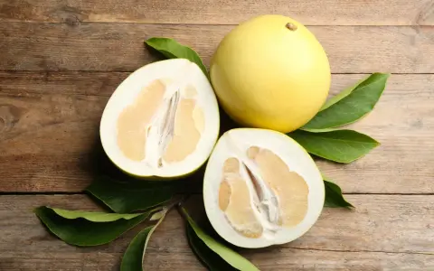 Całe i przekrojone pomelo na drewnianym tle. Czy pomelo jest zdrowe? Tak, to pyszny i odżywczy owoc.