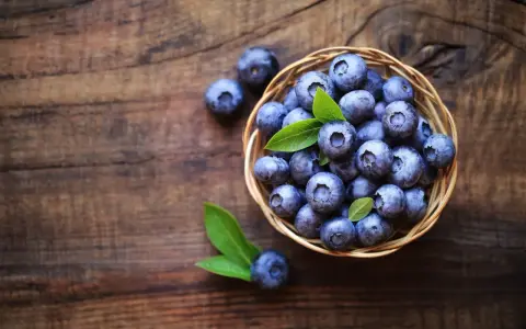 Koszyk pełen borówek na drewnianym tle. Zastanawiasz się, ile kcal mają borówki? Są niskokaloryczne i pełne witamin!