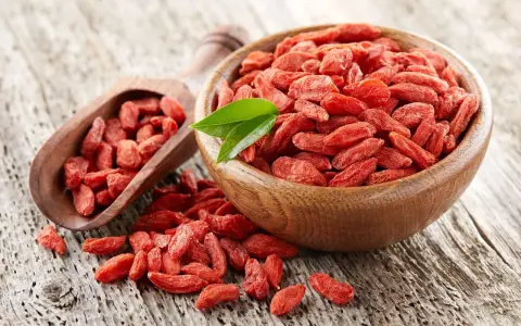 Suszone jagody goji w drewnianej misce i łopatce. Uważaj na jagody goji skutki uboczne, choć są zdrowe, mogą wchodzić w interakcje z lekami.