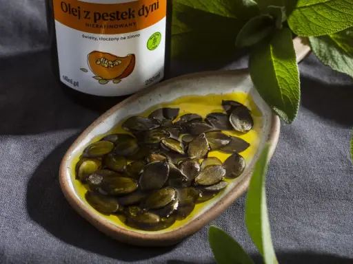 Olej z pestek dyni w naczyniu z pestkami. Warto znać olej z pestek dyni przeciwwskazania, choć jest on ceniony za swoje właściwości.