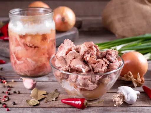 Słoik z mięsem i miska pełna smakołyków, cebula, czosnek, papryczki chili i liście laurowe. To składniki na obiady jak u babci przepisy.
