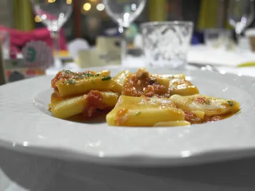Pyszny makaron paccheri w sosie pomidorowym, podany na białym talerzu.