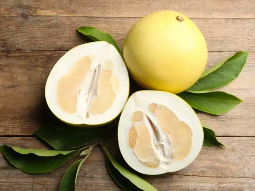 Całe i przekrojone pomelo na drewnianym tle. Czy pomelo jest zdrowe? Tak, to pyszny i odżywczy owoc.