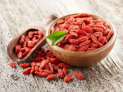 Suszone jagody goji w drewnianej misce i łopatce. Uważaj na jagody goji skutki uboczne, choć są zdrowe, mogą wchodzić w interakcje z lekami.