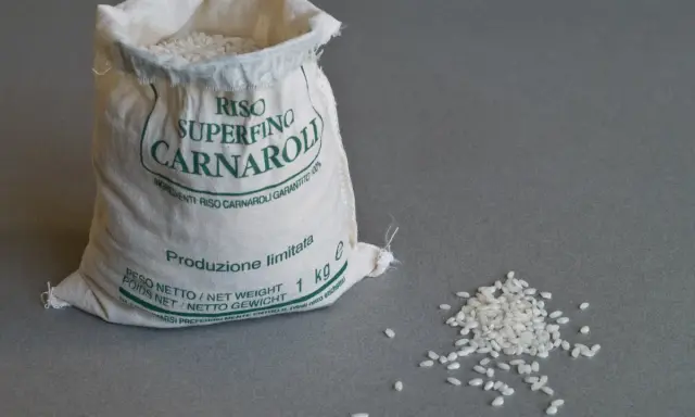 Worek z ryżem Carnaroli, idealnym do risotto. Kilka ziaren rozsypanych obok.