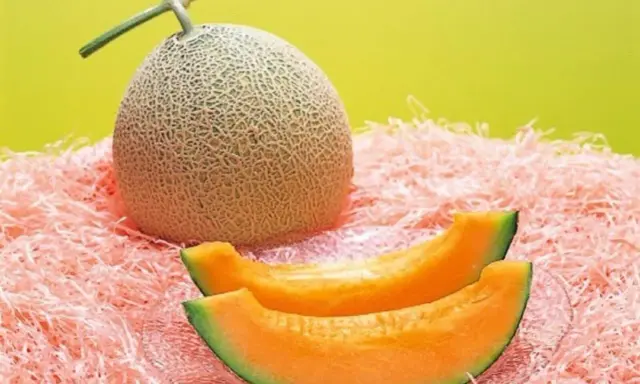 Cały melon i dwa kawałki soczystego, pomarańczowego miąższu na różowym tle. Czy to najdroższy owoc świata?