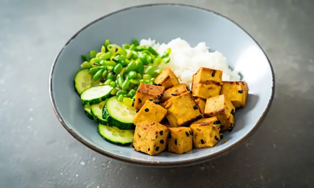Misternie pokrojone kostki tofu, które nie zawierają glutenu, podane z ryżem, ogórkiem i zielonym groszkiem.