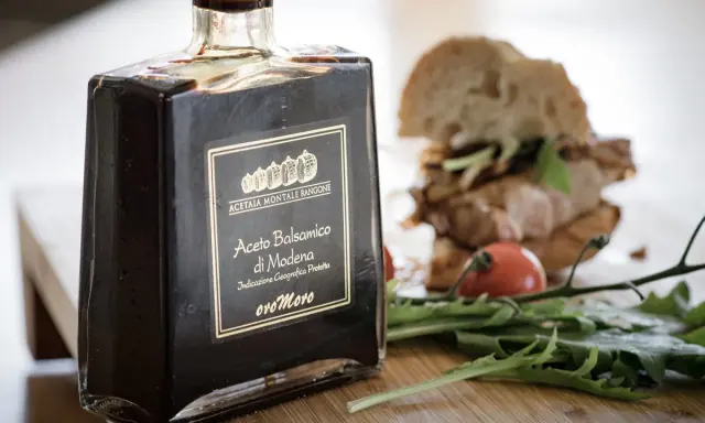Butelka octu balsamicznego z Modeny obok kanapki i rukoli. Ocet winny i balsamiczny to dwa różne smaki.