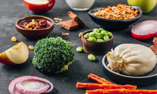 Składniki na dietę dr Budwig: brokuły, fasolka edamame, twaróg, jabłka, cebula, granola, suszone owoce, czekolada.