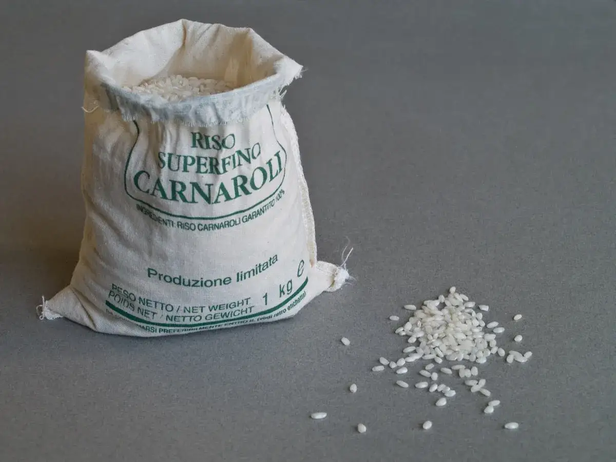 Worek z ryżem Carnaroli, idealnym do risotto. Kilka ziaren rozsypanych obok.