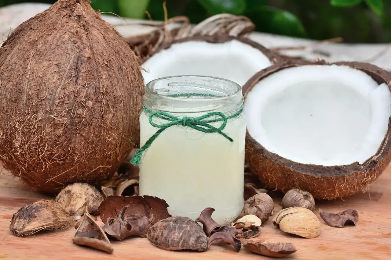 Słoik z olejem kokosowym, poł&oacute;wki kokosa i łupiny. Czy olej kokosowy się psuje? Ten naturalny produkt jest trwały.